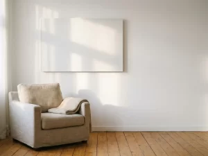 Infrarood verwarmingspaneel aan witte woonkamermuur, met fauteuil en houten vloer in warm ochtendlicht.